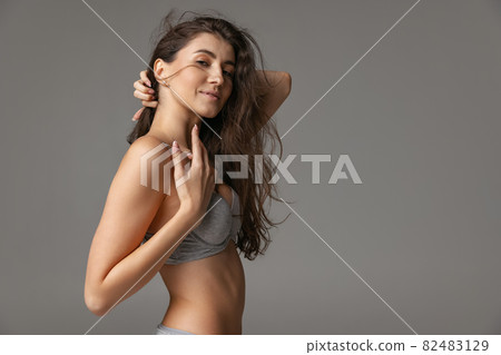 Half-length portrait of young beautiful slim woman in lingerie isolated over gray studio background. Natural beauty concept. Half-length portrait of young beautiful slim woman in lingerie isolated over gray studio background. Natural beauty concept. 82483129