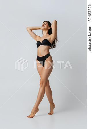 Portrait of young beautiful slim woman in lingerie posing isolated over gray studio background. Natural beauty concept. 82483226