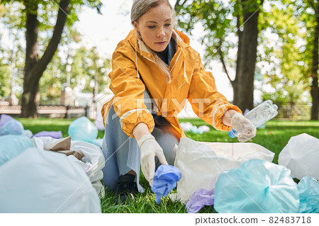 Woman volunteer cleaning up the park from garbage and rubbish 82483718