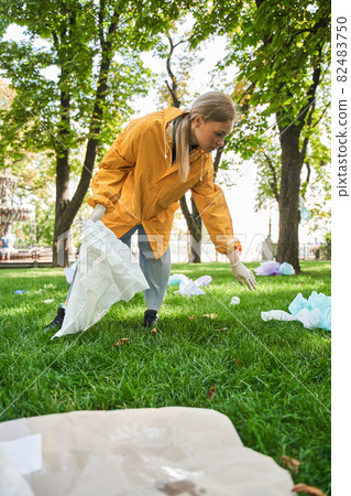 Active environmentalist wearing protective gloves cleaning the park Active environmentalist wearing protective gloves cleaning the park 82483750