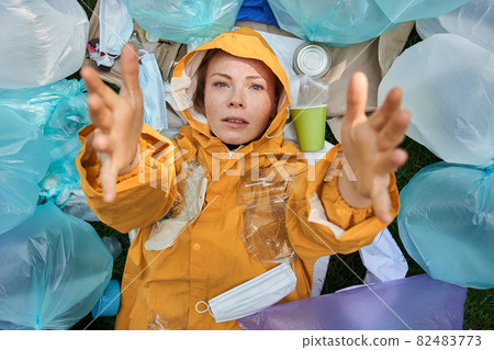 Unpleasantly surprised caucasian woman drowning in a pile of garbage Unpleasantly surprised caucasian woman drowning in a pile of garbage 82483773
