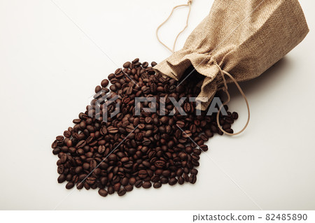 Roasted coffee beans scattered of the bag on white background Roasted coffee beans scattered of the bag on white background 82485890