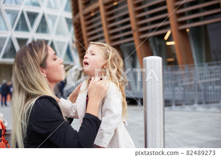 Young woman takes care of her crying daughter Young woman takes care of her crying daughter 82489273