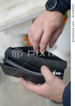Man holding an empty black leather wallet 82490887