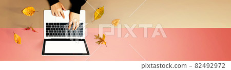 Autumn leaves with person using a laptop computer Autumn leaves with person using a laptop computer 82492972
