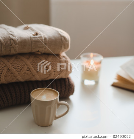 cozy comfortable home autumn still life with a candle, book, knitted sweaters and plaid cozy comfortable home autumn still life with a candle, book, knitted sweaters and plaid 82493092
