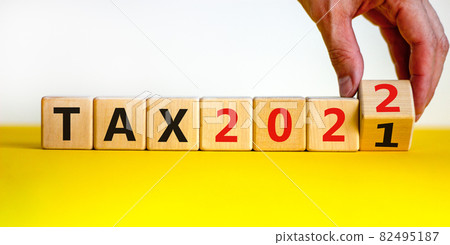 2022 tax new year symbol. Businessman turns wooden cubes and changes words 'Tax 2021' to 'Tax 2022'. Beautiful white background, copy space. Business, 2022 tax new year concept. 2022 tax new year symbol. Businessman turns wooden cubes and changes words 'Tax 2021' to 'Tax 2022'. Beautiful white background, copy space. Business, 2022 tax new year concept. 82495187