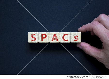 SPACs symbol. Wooden cubes with words 'SPACs, special purpose acquisition companies' on beautiful black background, copy space. Businessman hand. Business and SPACs concept. SPACs symbol. Wooden cubes with words 'SPACs, special purpose acquisition companies' on beautiful black background, copy space. Businessman hand. Business and SPACs concept. 82495200