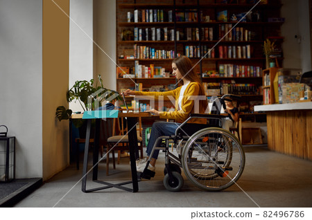 Disabled female student in wheelchair using laptop 82496786