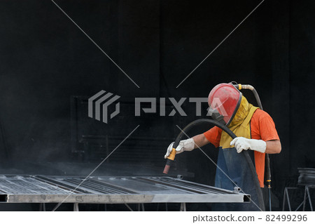 Industrial worker cleaning surface of steel with sandblast Industrial worker cleaning surface of steel with sandblast 82499296
