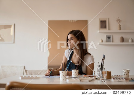 Beautiful Female Artist In Her Studio. Female drawing in album with watercolor paints and paintbrush Beautiful Female Artist In Her Studio. Female drawing in album with watercolor paints and paintbrush 82499770