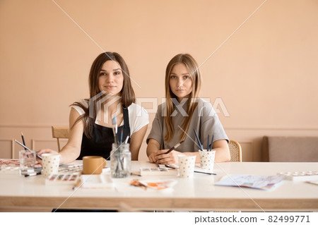 Front view of four beautiful caucasian female at art workshop. A young teacher teaches drawing Front view of four beautiful caucasian female at art workshop. A young teacher teaches drawing 82499771