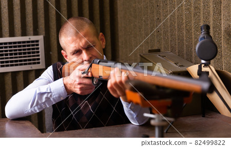 Man shoots semi-automatic rifle at shooting range Man shoots semi-automatic rifle at shooting range 82499822