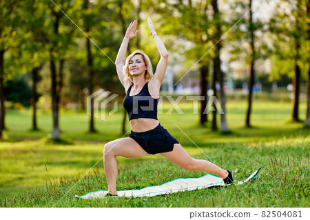 Smiling slim white woman makes yoga asanas outdoors. Smiling slim white woman makes yoga asanas outdoors. 82504081