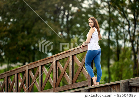 Graceful white woman stands in park at daytime. Graceful white woman stands in park at daytime. 82504089