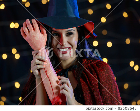 Woman in Halloween costume showing bloody human arm 82508643