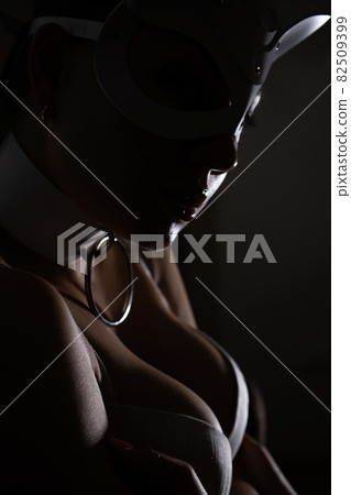 Woman in mask touching breast 82509399