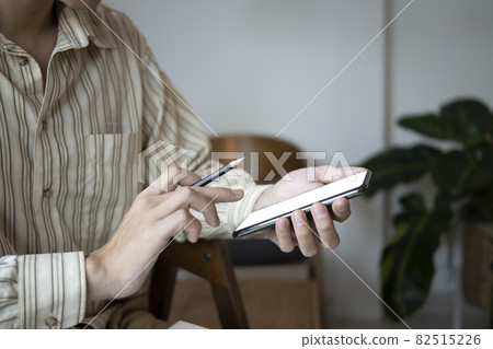 Cropped shot businessman holding pencil and using smart phone. 82515226