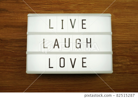 Live Laugh Love word in light box on wooden background 82515287