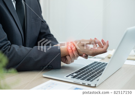 Businessman grasping the painful wrist caused by prolonged work on a laptop keyboard. Wrist numbness Arthritis While working at the office Businessman grasping the painful wrist caused by prolonged work on a laptop keyboard. Wrist numbness Arthritis While working at the office 82517150