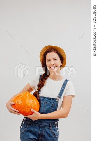 Farmer stands on a white background and holds an orange pumpkin in her hands. Farmer stands on a white background and holds an orange pumpkin in her hands. 82518085