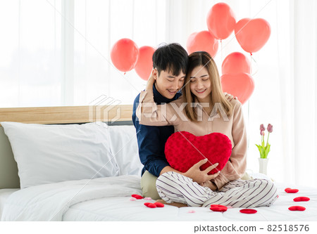 Asian man and woman hugging on bed 82518576
