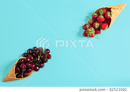 Berries in waffle cones - strawberry and black cherry on blue ba Berries in waffle cones - strawberry and black cherry on blue ba 82521092
