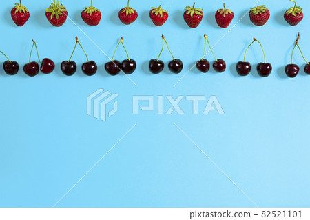 Fresh cherries and strawberries on blue background, top view Fresh cherries and strawberries on blue background, top view 82521101