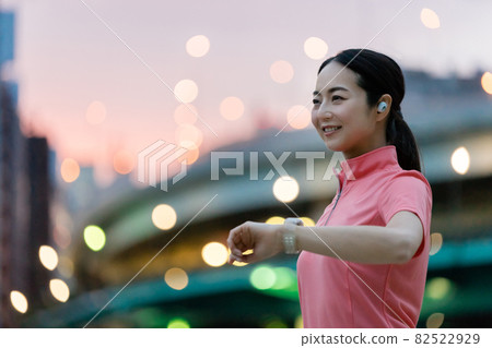 A woman in sportswear operating a smartwatch 82522929