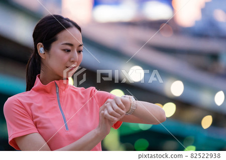 A woman in sportswear operating a smartwatch 82522938