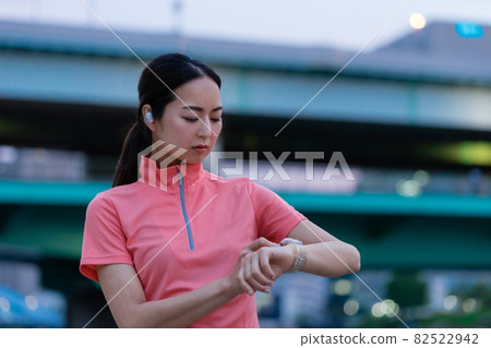A woman in sportswear operating a smartwatch A woman in sportswear operating a smartwatch 82522942