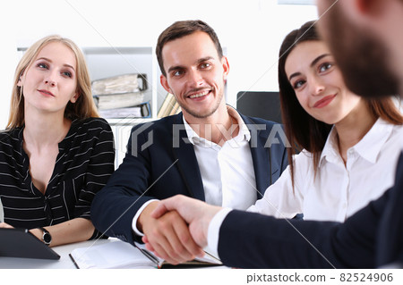 Smiling man in suit shake hands as hello in office Smiling man in suit shake hands as hello in office 82524906