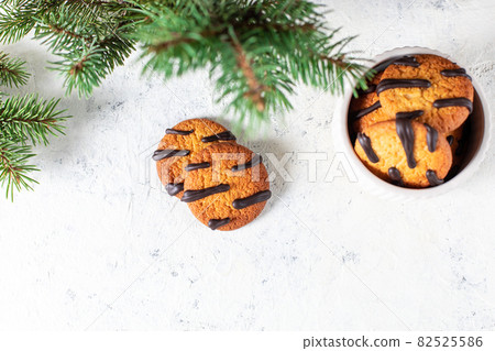 orange cookies with black stripes in bowl and fir tree branches. Christmas dessert. Concept for children new year orange cookies with black stripes in bowl and fir tree branches. Christmas dessert. Concept for children new year 82525586