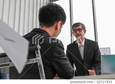 Portrait shot of elderly Asian businessman leader blaming a young employee with serious facial expression. An old man standing and throwing document papers in the air while berating subordinate Portrait shot of elderly Asian businessman leader blaming a young employee with serious facial expression. An old man standing and throwing document papers in the air while berating subordinate 82527835