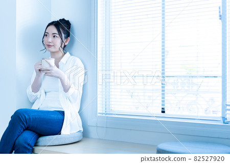 在陽光明媚的客廳裡喝杯咖啡放鬆的女人 在陽光明媚的客廳裡喝杯咖啡放鬆的女人 82527920
