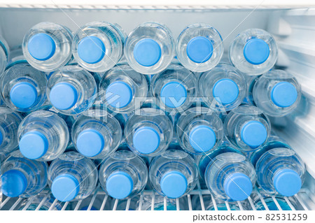 Rows of many transparent plastic bottles with drinking water supply in white refrigerator. Mineral water stack storage in fridge to drink on hot summer day. Healthcare and dehydration prevention Rows of many transparent plastic bottles with drinking water supply in white refrigerator. Mineral water stack storage in fridge to drink on hot summer day. Healthcare and dehydration prevention 82531259