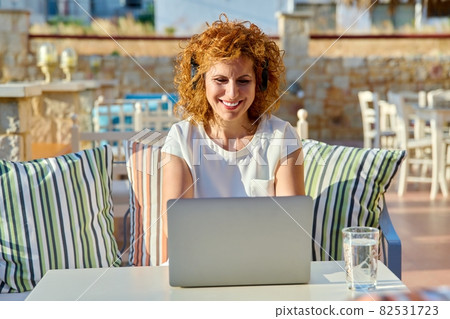 Positive smiling woman working with laptop outdoors. 82531723