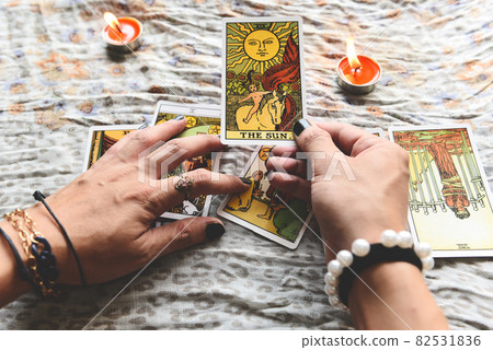 Show fortune tellers of hands holding tarot cards and tarot reader with candle light on the table, Performing readings magical performances, Things mystical astrologists forecasting concept Show fortune tellers of hands holding tarot cards and tarot reader with candle light on the table, Performing readings magical performances, Things mystical astrologists forecasting concept 82531836