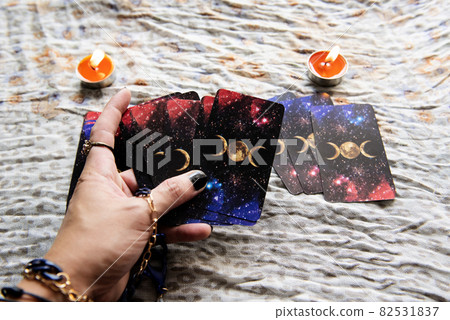 Show fortune tellers of hands holding tarot cards and tarot reader with candle light on the table, Performing readings magical performances, Things mystical astrologists forecasting concept 82531837