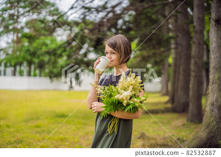 Young woman holds in her hands with a paper tumbler with coffee or tea 82532887