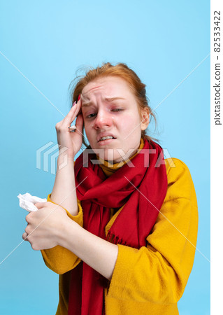 Cropped vertical portrait of young Caucasian girl feeling sick, having a cold isolated over blue background Cropped vertical portrait of young Caucasian girl feeling sick, having a cold isolated over blue background 82533422