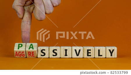 Passively or aggressively symbol. Businessman turns cubes and changes the word passively to aggressively. Psychological and passively or aggressively concept. Beautiful orange background, copy space. Passively or aggressively symbol. Businessman turns cubes and changes the word passively to aggressively. Psychological and passively or aggressively concept. Beautiful orange background, copy space. 82533799