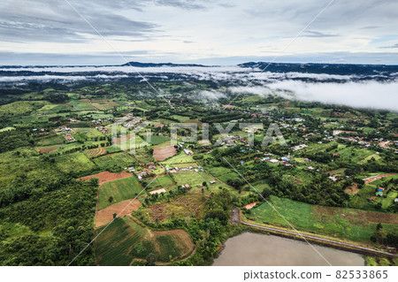 Agricultural green field farmland with fog in countryside on rainy day Agricultural green field farmland with fog in countryside on rainy day 82533865