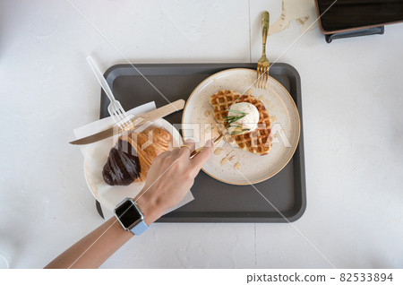 Hand using spoon scooping ice cream waffle and croissant on white table Hand using spoon scooping ice cream waffle and croissant on white table 82533894