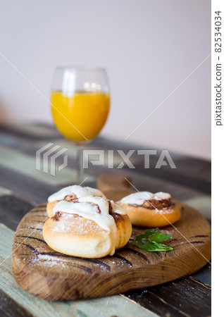 Homemade buns with cinnamon and a glass of juice Homemade buns with cinnamon and a glass of juice 82534034