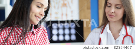 Smiling female patient signs medical form at clinic meeting with doctor Smiling female patient signs medical form at clinic meeting with doctor 82534467