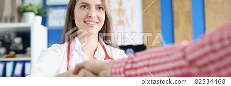 Smiling young caucasian female doctor shaking hands with greeting and meeting patient at hospital 82534468