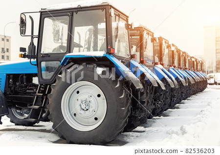 Many different tractors standing in row at agricultural fair for sale outdoors.Equipment for agriculture.Heavy industrial machines presented to agricultural exhibition. Agribusiness leasing concept 82536203