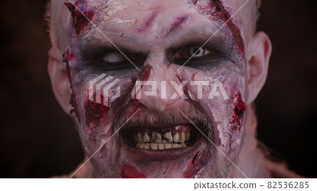 Creepy man scary wounded bloody scars face Halloween undead guy blows smoke from nose, smiles Creepy man scary wounded bloody scars face Halloween undead guy blows smoke from nose, smiles 82536285