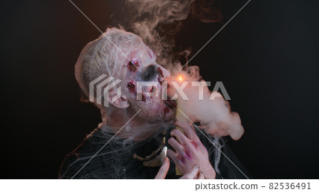 Frightening man with Halloween zombie bloody makeup spells conjures over candle, voodoo rituals Frightening man with Halloween zombie bloody makeup spells conjures over candle, voodoo rituals 82536491